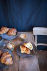 Croissants with cappuccinos on a rustic wooden table — Stock Photo