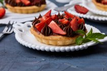 Mini tarta con mermelada de fresa, servida con fresas frescas y ganache de chocolate - foto de stock