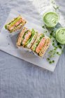 Sandwich de tostadas con salmón, pepino, aguacate, caviar y queso cremoso, servido con smoothy verde - foto de stock
