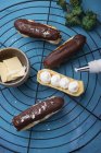 Chocolate eclairs being filled with whipped soya cream — Stock Photo
