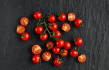 Tomate cherry fresco con gotas de albahaca sobre un fondo oscuro - foto de stock