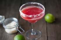 Watermelon margarita in glass with salt rim and limes on background — Stock Photo