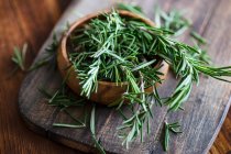 Organic fresh rosemary herb on textile napkin on wooden table — Stock Photo