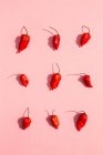 Nine fresh red chilli peppers on a pink surface — Stock Photo