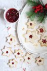 Biscotti di stelle pieni di marmellata con rami di abete e vaso di marmellata — Foto stock