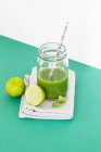 Un frullato di lime verde e basilico in un bicchiere con una cannuccia — Foto stock