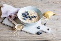 Porridge with banana and blueberries, ingredients on wooden table — Stock Photo