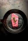 Una bistecca di manzo con rosmarino in una padella — Foto stock