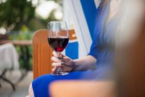 Une femme assise sur une chaise de plage avec un verre de vin rouge — Photo de stock