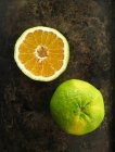 A halved and whole ugli fruit on a dark surface — Stock Photo