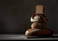 Four different breads, stacked on dark background — Stock Photo