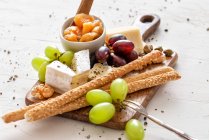 Käseplatte mit Apfelchutney, Nüssen, Kapern, Trauben und Semmelspießen — Stockfoto