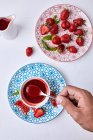 Hand hält Löffel hausgemachte Erdbeersoße und frische Erdbeeren auf dem Teller — Stockfoto
