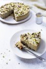 Gâteau au fromage aux pistaches au chocolat blanc servi sur assiette blanche avec fourchette à dessert — Photo de stock