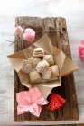 Gluten-free layered biscuits with pink icing and pink paper flowers on a rustic wooden board — Stock Photo