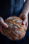 Hands holding loaf of freshly baked bread — Stock Photo