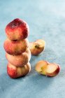 Stacked peaches with water drops and halved one on rustic concrete surface — Stock Photo