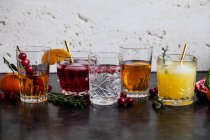 Várias bebidas alcoólicas com uísque, bourbon, vodka, cranberry, laranjas, romãs, alecrim e tomilho — Fotografia de Stock