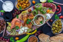 Assiette antipasti avec divers légumes, crevettes, trempettes, fruits, pain et poulet — Photo de stock