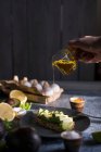 Оливковое масло выливается из стеклянного кувшина на хлеб авокадо — стоковое фото