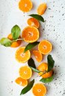 Orangen mit Blättern, ganz, halbiert und Scheiben — Stockfoto