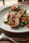 Woodfire-grilled salmon with Swiss chard and tahini salad, tomato and cucumber - foto de stock