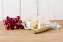 Queso Camembert con cuchillo y uvas rojas frescas - foto de stock