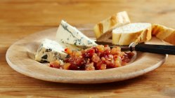 Chutney de pêra doce com pimenta servida com queijo azul e baguete fatiada em prato de madeira — Fotografia de Stock
