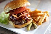 Hamburger au bacon juteux de luxe avec frites et cornichon cornichon — Photo de stock