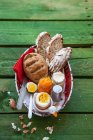Una cesta de desayuno con un huevo cocido, pan integral y mermelada de naranja y zanahoria - foto de stock