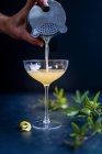 Barkeeper gießt Cocktail in Glas mit Zitrone und Minze — Stockfoto
