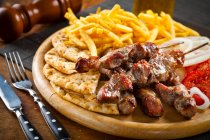 Souvlaki de porco grego com batatas fritas e pão grelhado — Fotografia de Stock