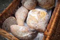 Divers rouleaux de pain frais dans un panier en osier — Photo de stock