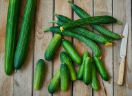 Fresh cucumbers on a wooden background with knife — Stock Photo