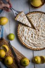 Hand picking piece of lemon tart with meringue top from plate — Stock Photo