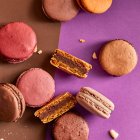 Assortment of colorful macarons on purple and brown background — Stock Photo