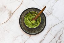 Close-up shot of delicious bowl of hemp pesto with a wooden spoon — Stock Photo