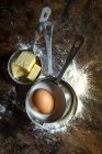 Tazas de medir con harina, mantequilla, azúcar y un huevo - foto de stock