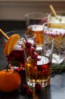 Varias bebidas alcohólicas con whisky, bourbon, vodka, arándano, naranjas, granadas, romero y tomillo - foto de stock