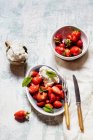 Whipped cream in jug with fresh strawberries in bowls — Stock Photo