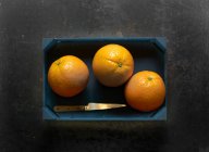 Three oranges in a wooden crate — Stock Photo
