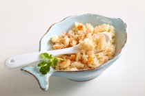 Viande de crabe râpée dans un petit bol avec une cuillère et des feuilles de coriandre — Photo de stock