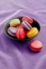 Macarons in schwarzer Schale auf violettem Tuch — Stockfoto