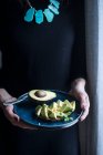 A woman holding a plate of avocado bread — Stock Photo