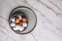 Eier unterschiedlicher Farbe in Schale auf Marmoroberfläche — Stockfoto