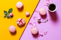Pink macaroons with rose flowers and coffee cup — Stock Photo