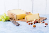 Fromage à pâte dure, noisettes et raisins sur planche de bois — Photo de stock