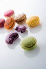 Macaron colorati interi e screpolati con riflessi su sfondo bianco — Foto stock