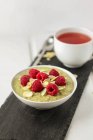 Porridge di matcha con lamponi e scaglie di mandorle e tazza di tè — Foto stock