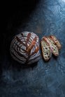 Sourdough bread loaf and slices on rustic surface — Stock Photo